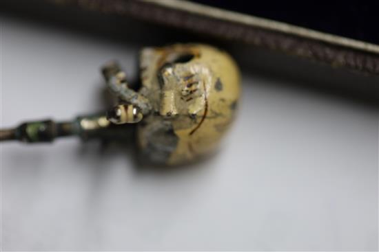 A 19th century French? base metal and cream enamel skull head stick pin, in the manner of Trouve & Cadet-Picard, overall 73mm.